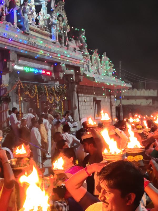 ದೇವಸ್ಥಾನದ ಬಾಗಿಲಿನ ಮುಂದೆ ಉರಿಯುವ ಆರತಿಗಳನ್ನು ಹೊತ್ತು ಸಾಗುತ್ತಿರುವ ಭಕ್ತರು
