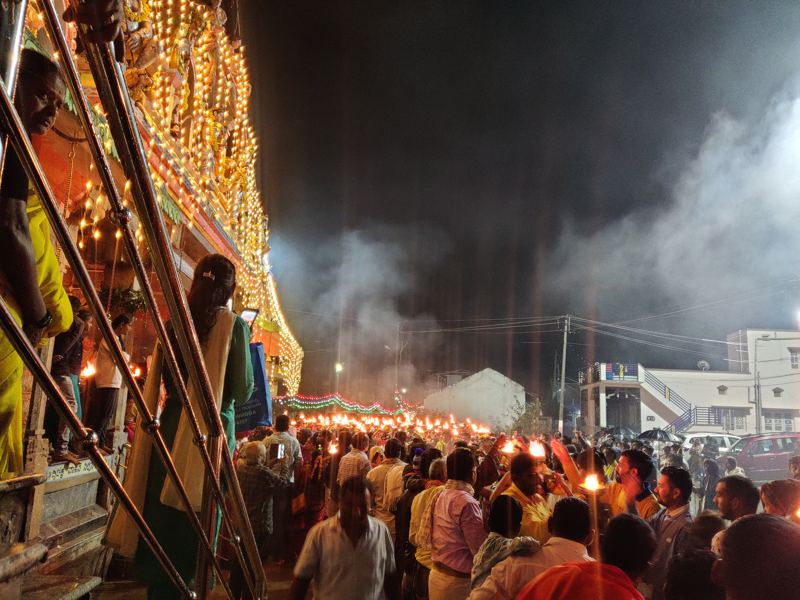 ದೀಪಗಳಿಂದ ಅಲಂಕೃತ ದೇವಸ್ಥಾನದ ಮೆಟ್ಟಿಲುಗಳಿಂದ ಕಾಣುವ, ಬೀದಿಯುದ್ದಕ್ಕೂ ಸಾಗುವ ಆರತಿಗಳ ಸಾಲು
