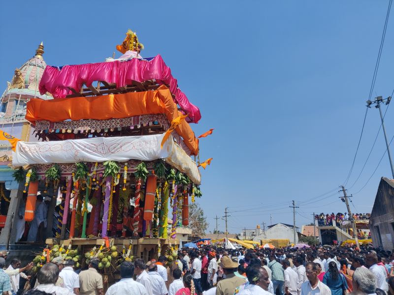ಬಣ್ಣದ ಬಟ್ಟೆ, ಹೂವಿನ ಹಾರ ಮತ್ತು ತೆಂಗಿನಕಾಯಿಗಳಿಂದ ಅಲಂಕರಿಸಿದ ರಥ, ಸುತ್ತಲೂ ಭಕ್ತರ ದೊಡ್ಡ ಜನಸಂದಣಿ