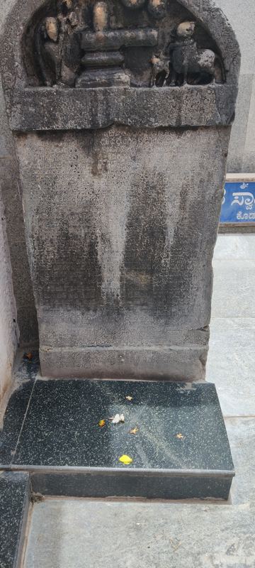 ಶಾಸನ ಕಲ್ಲಿನ ಸಮೀಪ ನೋಟ. ಕಲ್ಲಿನ ಮೈಮೇಲೆ ಸಾಲು ಸಾಲಾಗಿ ಕೆತ್ತಿದ ಹಳಗನ್ನಡ ಅಕ್ಷರಗಳು